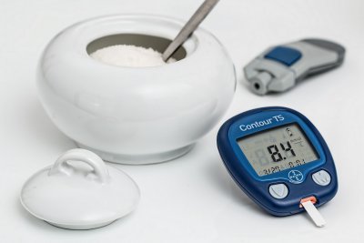 A pot of sugar next to a blood sugar reader for diabetes, hypoglycaemia, and reactive hypoglycaemia