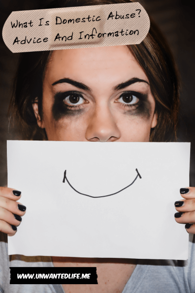 A photo of a white woman which smudged make-up holding a piece of paper over their mouth with a smile drawn on it to hide her real expression. Across the top of the image is the article title - What Is Domestic Abuse? Advice And Information