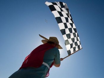 A South America man waving the chequered flag to represent the topic of the article - Race Across The World, With Your Mum