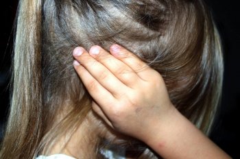 A photo of a little girl covering her ears in fear