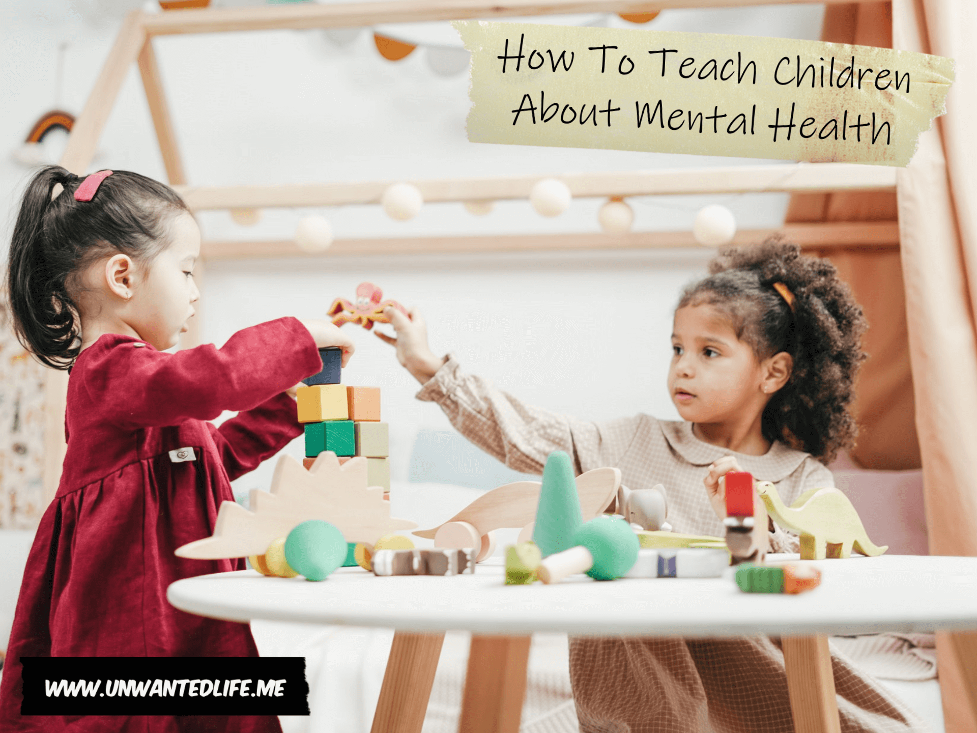A photo of a little black girl and a little east Asian girl playing together around a table to represent the topic of the article - How To Teach Children About Mental Health