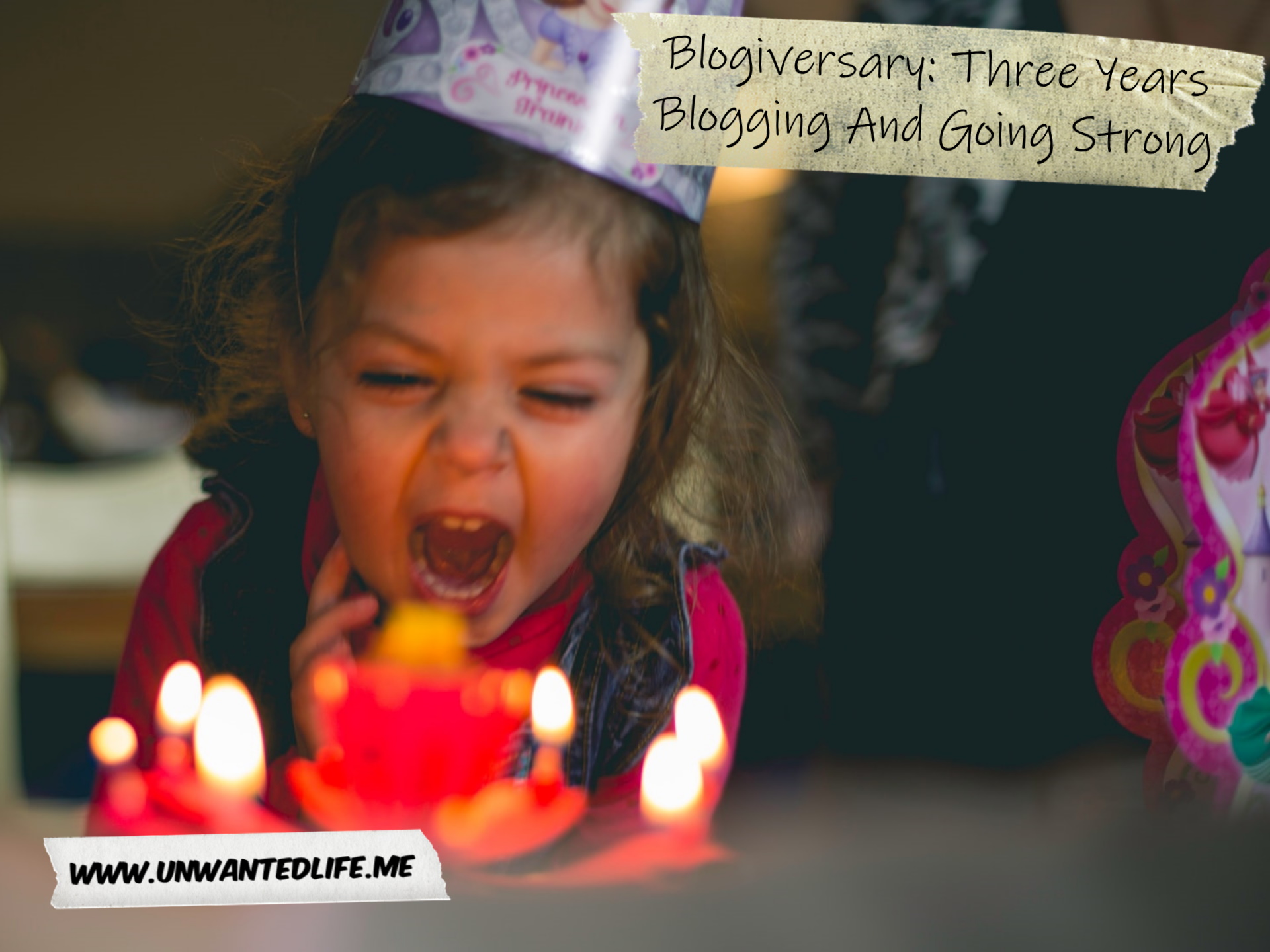 A white child enthusiastically blowing out candles on a cake while wearing a birthday hat to represent the topic of the article - Blogiversary: Three Years Blogging And Going Strong