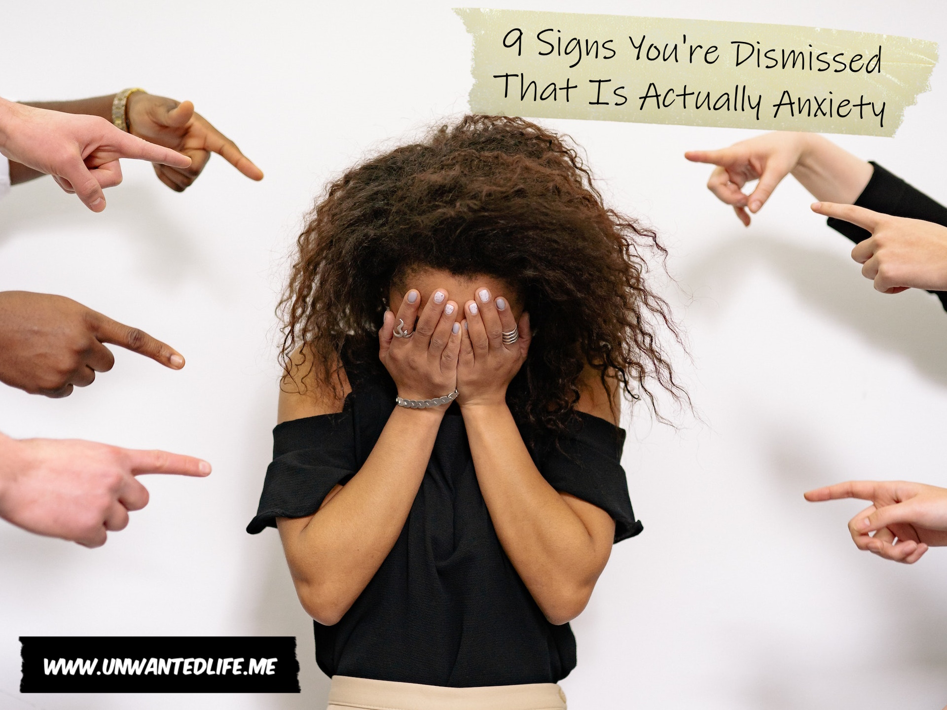 A photo of a Black woman with her head in her hands with several hands pointing at her to represent the topic of the article - 9 Signs You're Dismissed That Is Actually Anxiety