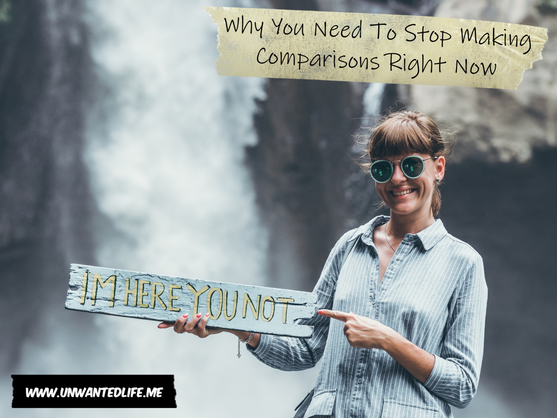 A photo of a White woman standing in front of a waterfall holding a sign that says "I'm here you not" to represent the topic of the article - Why You Need To Stop Making Comparisons Right Now