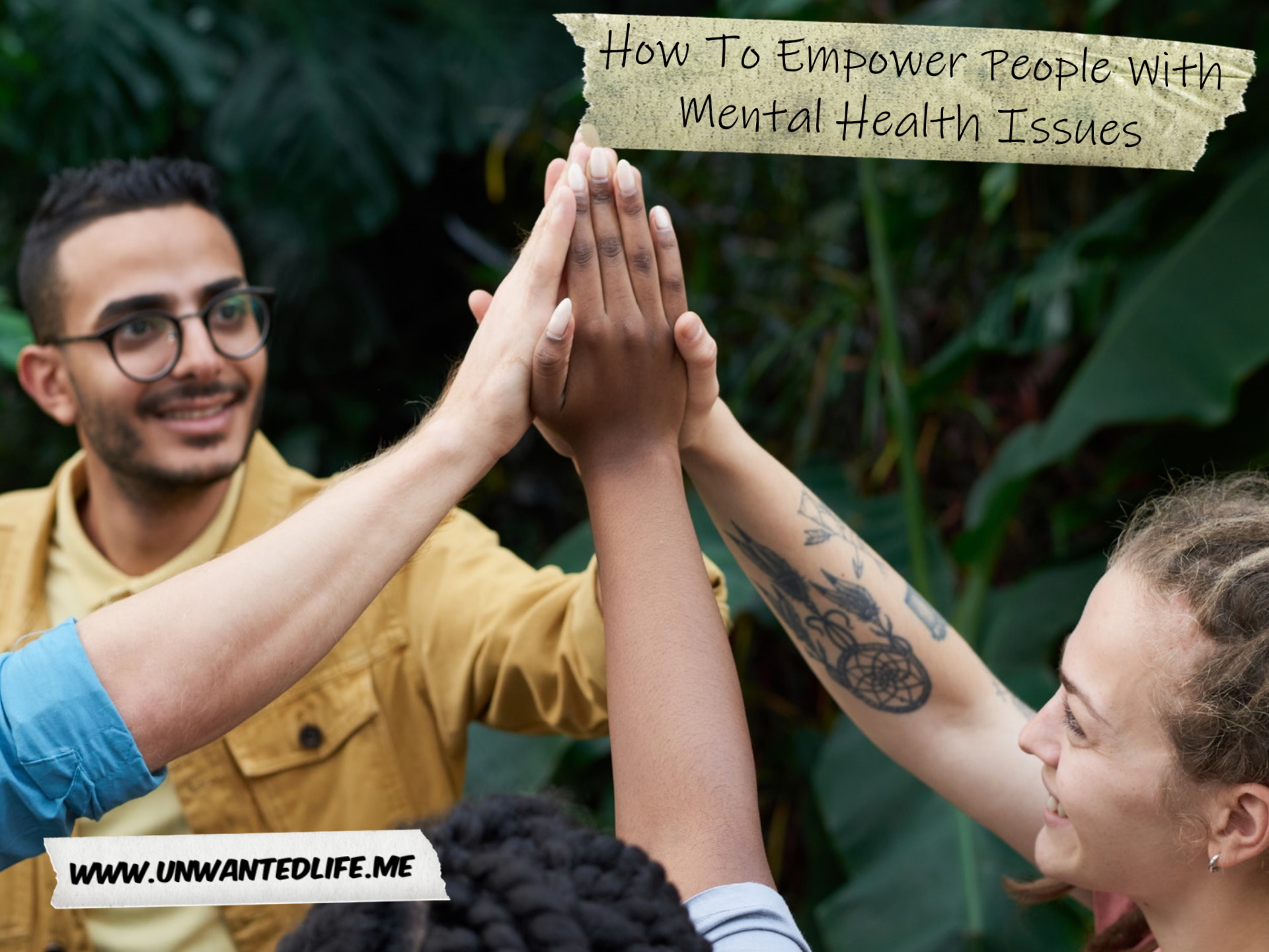 A photo of four people from different ethnic groups showing support for each other with a group high five to represent the topic of the article - How To Empower People With Mental Health Issues - Wellbeing - Unwanted Life