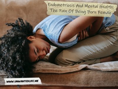 A photo of a Black woman kneeled over in pain on the sofa with her hands on her stomach to represent the topic of the article - Endometriosis And Mental Health: The Pain Of Being Born Female