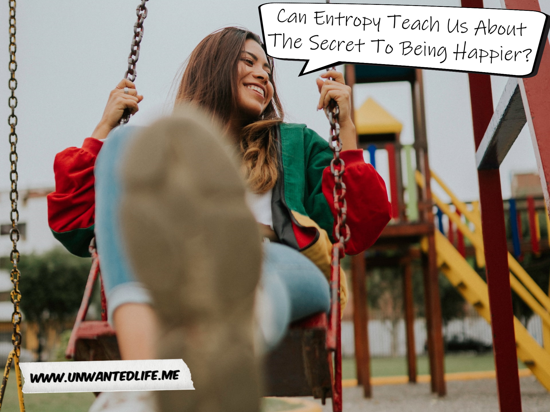 A photo of a White woman swinging on swing in a playground whilst smiling to represent the topic of the article - Can Entropy Teach Us About The Secret To Being Happier?