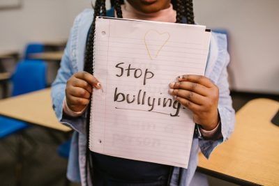 A photo of a Black girl holding a sign that says, "stop bullying"