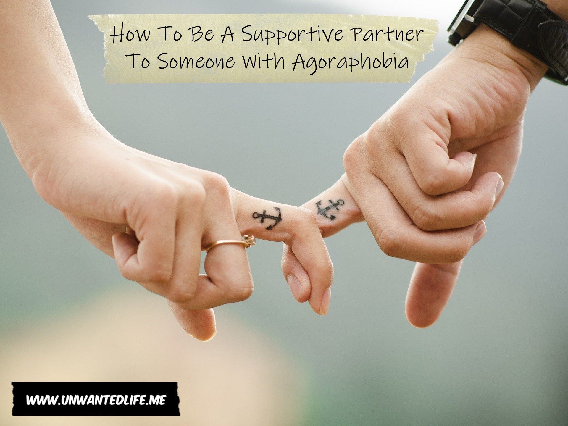 A photo of a couple holding hands by holny holding to of their fingers together, both of which have a matching anchor tattoo to represent the topic of the article - How To Be A Supportive Partner To Someone With Agoraphobia
