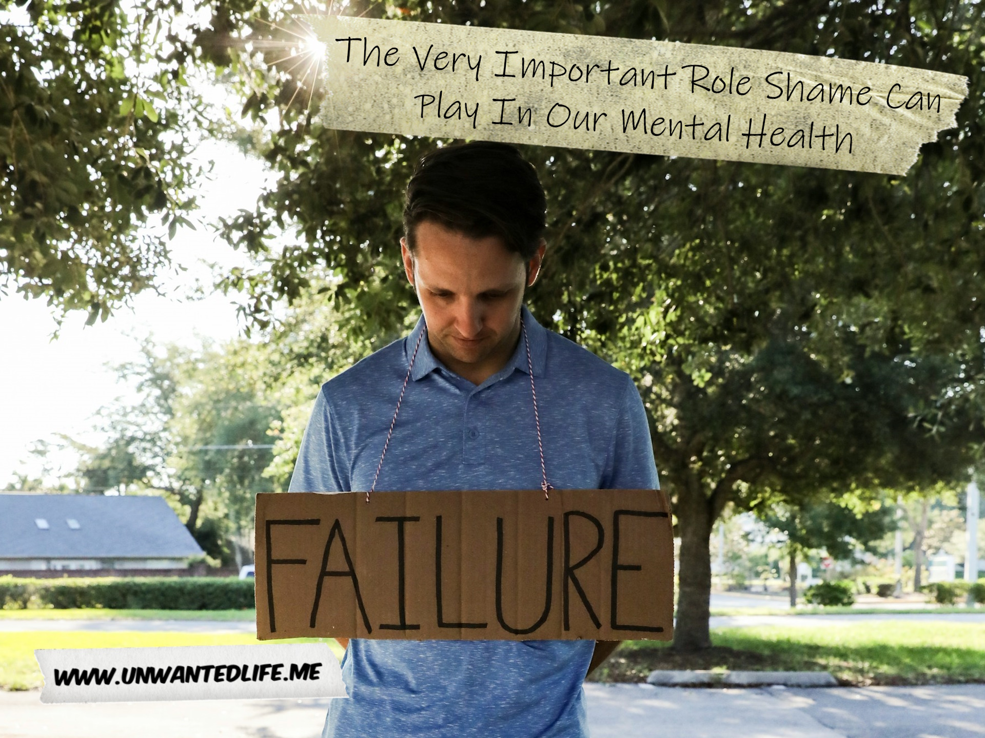 A photo of a man wearing a sign that says "Failure" to represent the topic of the article - The Very Important Role Shame Can Play In Our Mental Health