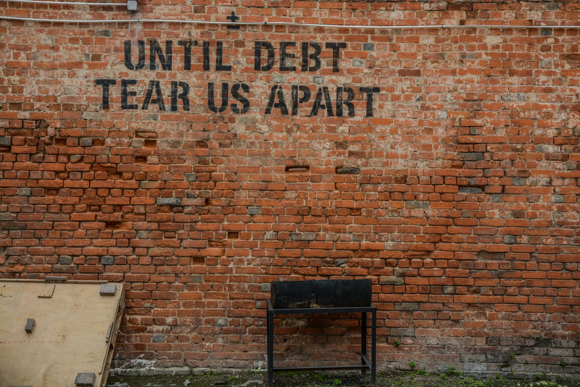 A photo of graffiti on the wall which says, "Until debt tear us part" to represent the topic of the article - My Experience Of Living In An Overdraft Debt Trap