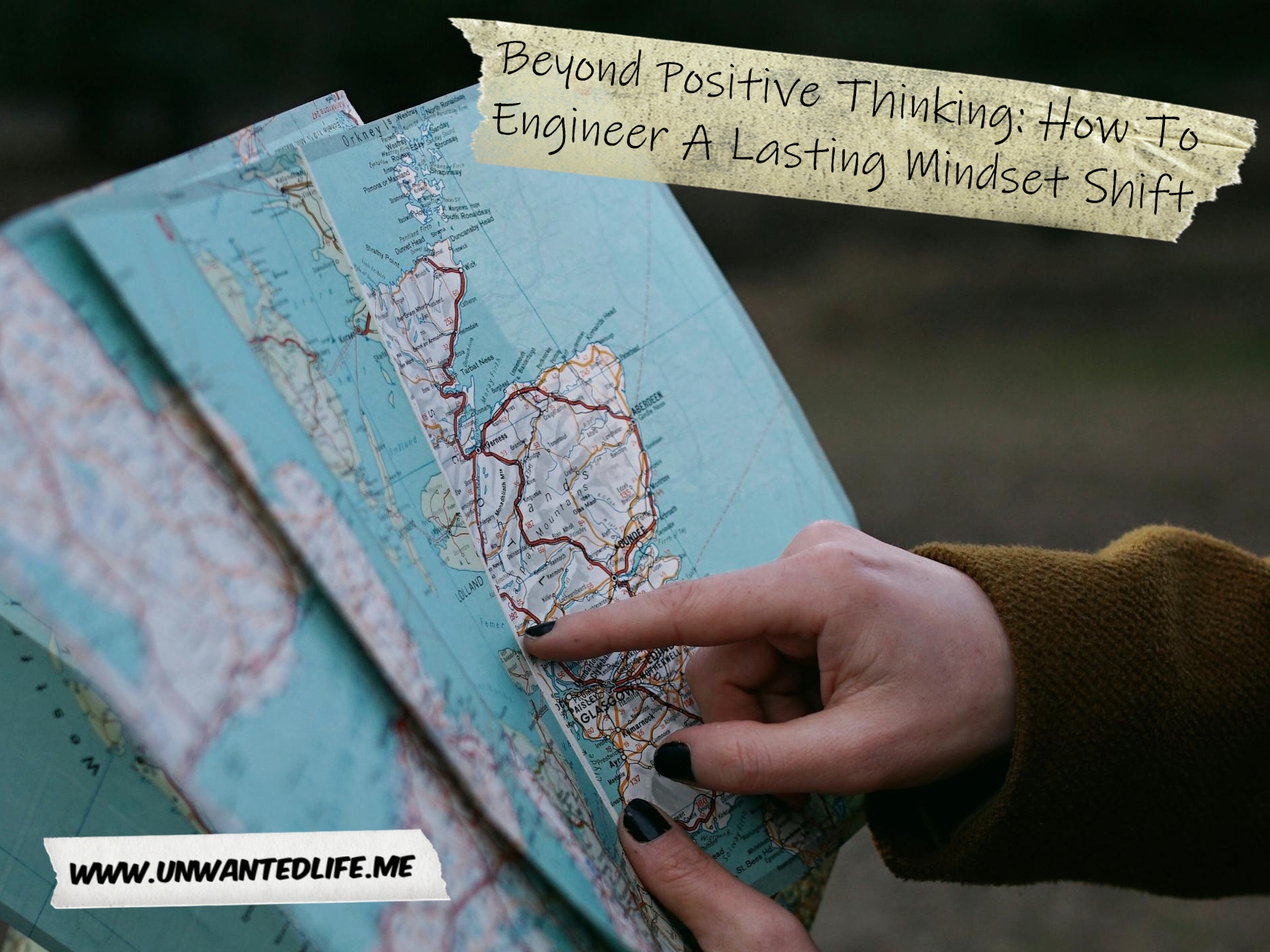 An image of a White person with painted black finger nails looking at a map. to represent the topic of the article - Beyond Positive Thinking: How To Engineer A Lasting Mindset Shift