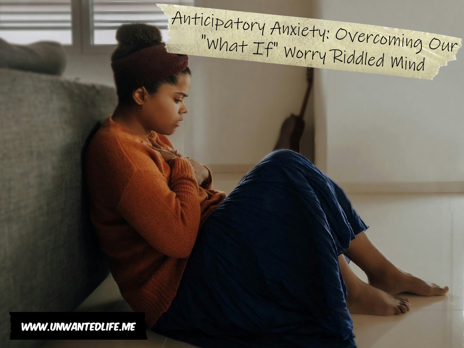 A photo of a young Black woman sitting on the floor and leaning against the back of a sofa, with their hand on their chest trying to calm down. This represents the topic of the article - Anticipatory Anxiety: Overcoming Our "What If" Worry Riddled Mind