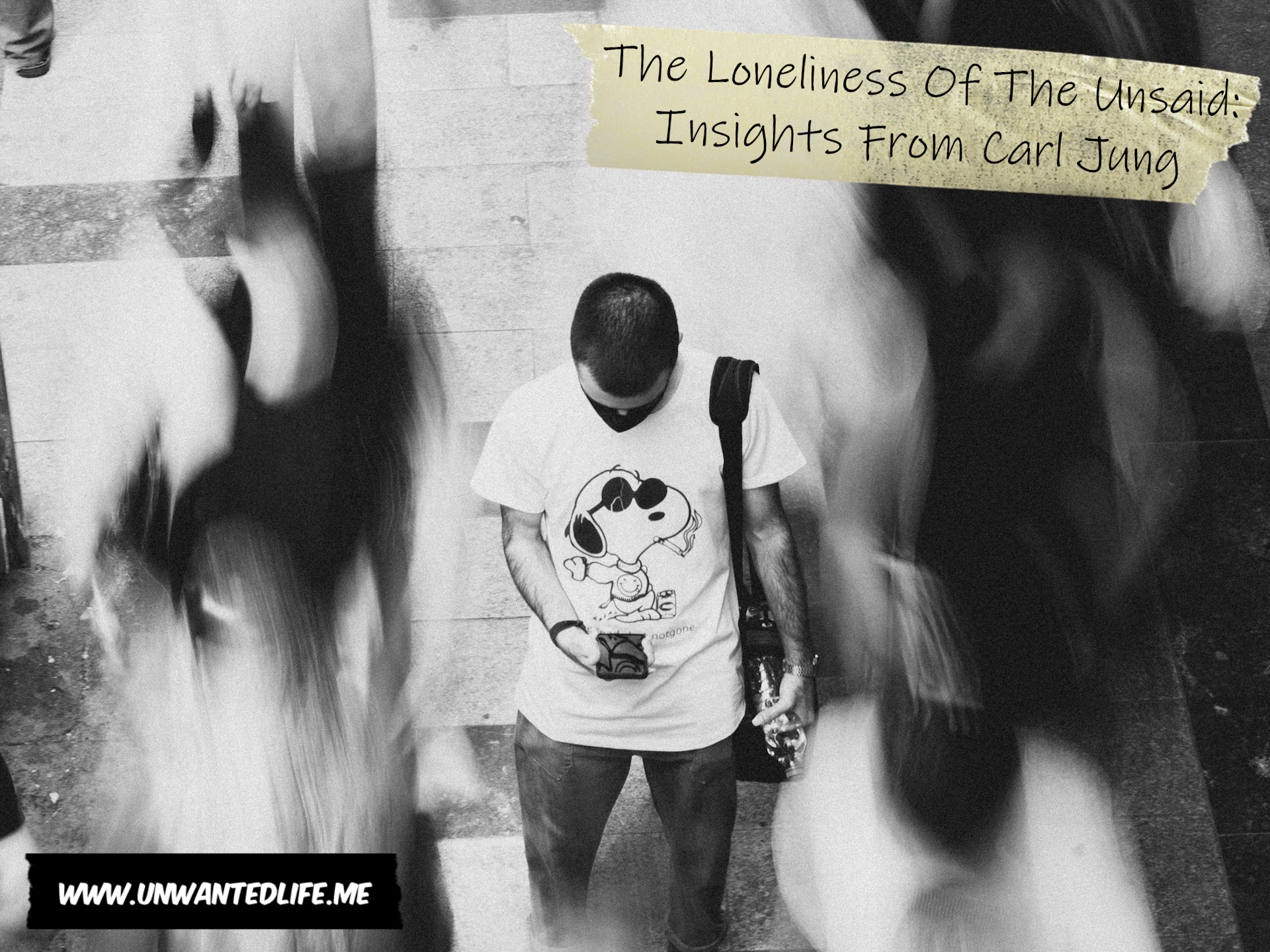 A photo of a man standing in a street with blurred people walking past him to represent the topic of the article - The Loneliness Of The Unsaid: Insights From Carl Jung