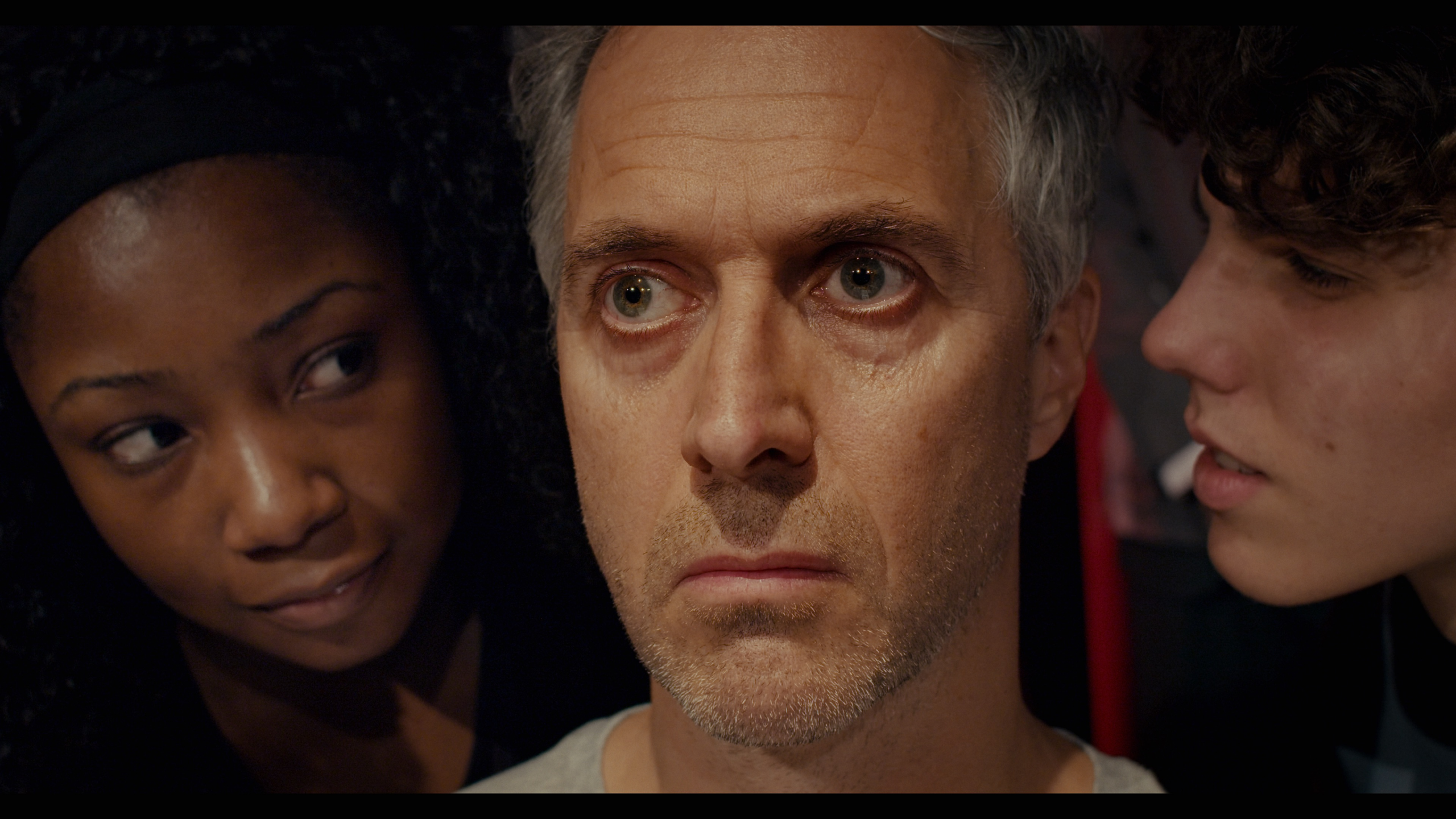 A still from The Directors: Marcus, Marcus Coates (2022). Courtesy of Artangel, taken as part of the psychosis art project, which is a closeup of Marcus Coates with two actors whispering in his ears