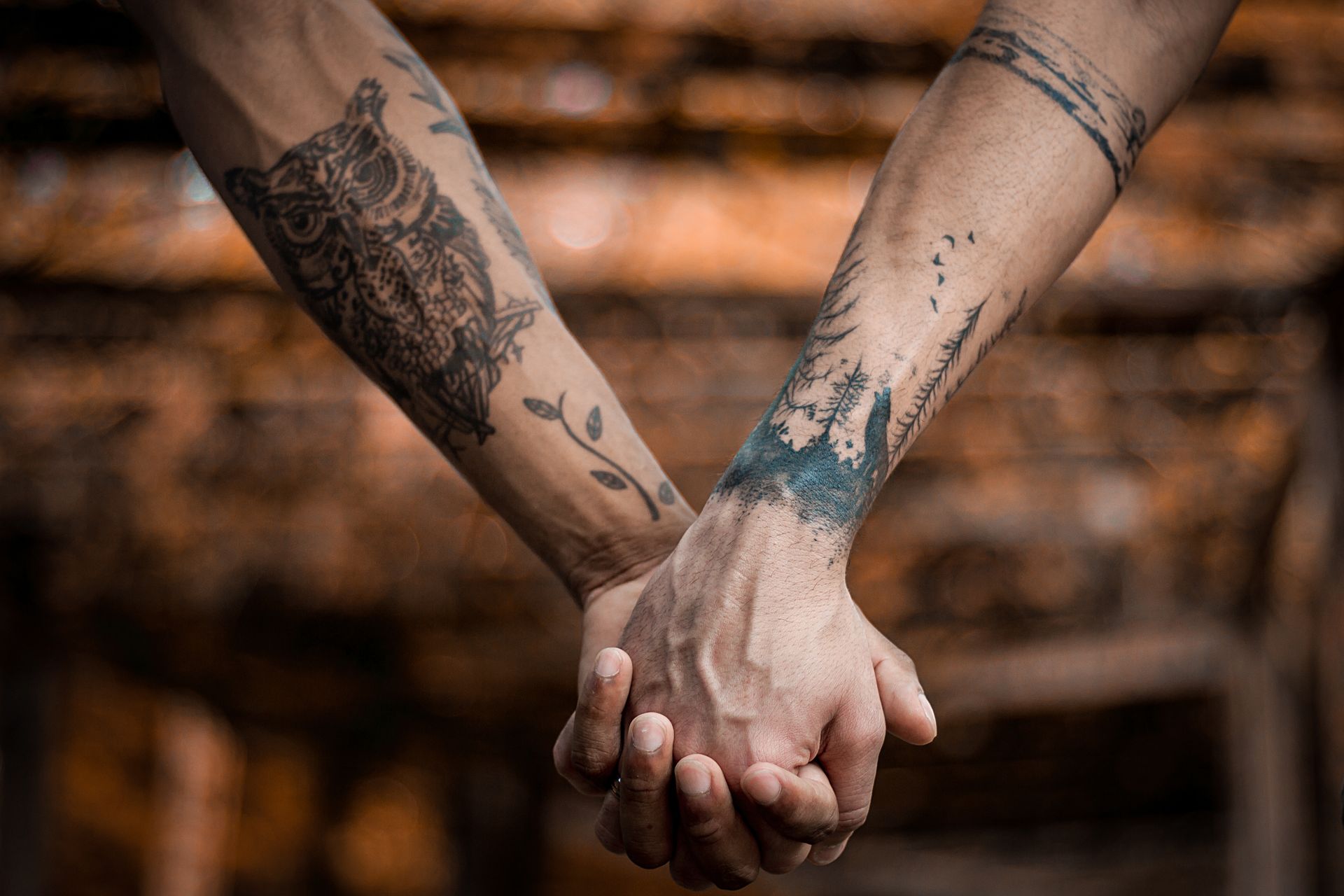 A close up photo of two people holding hands showing off their arm sleeve tattoos to represent the topic of the article - Unwanted Life: My Body Modification Journey