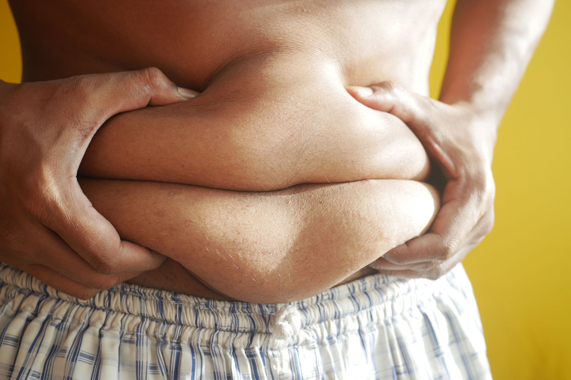 A photo of someone squeezing their fat belly
