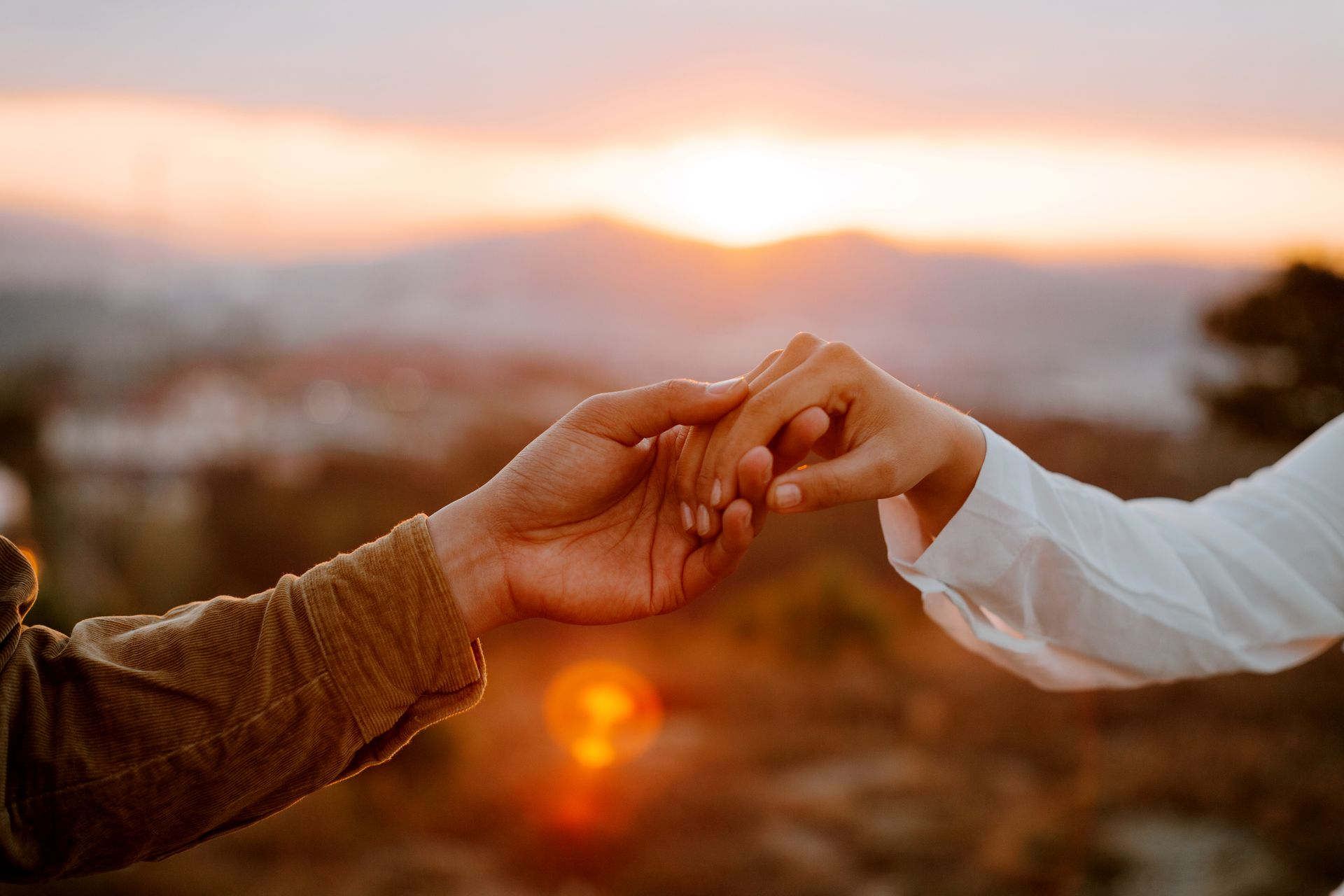 A couple holding hands with a sunset in the background to represent the topic of the post - A First-Hand Account Of Supporting A Partner With Anxiety
